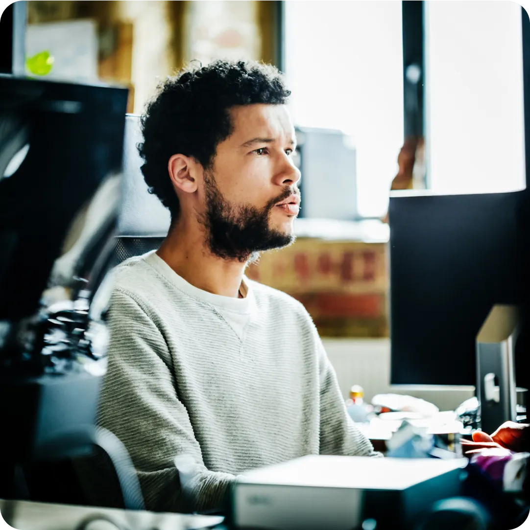 Professional sitting at their desk with a monitor in front of them evaluating which Duo edition to choose for their organization and 30-day free trial.