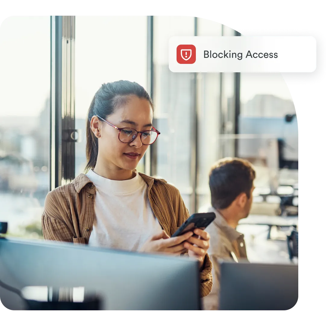 Professional reviewing mobile security alert as Duo blocks unauthorized access in an office setting.