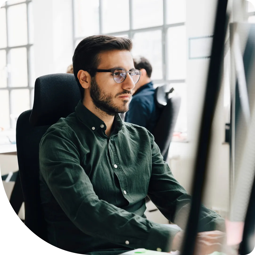 Focused professional with glasses reviewing Duo documentation and searching the knowledge base on a desktop monitor.