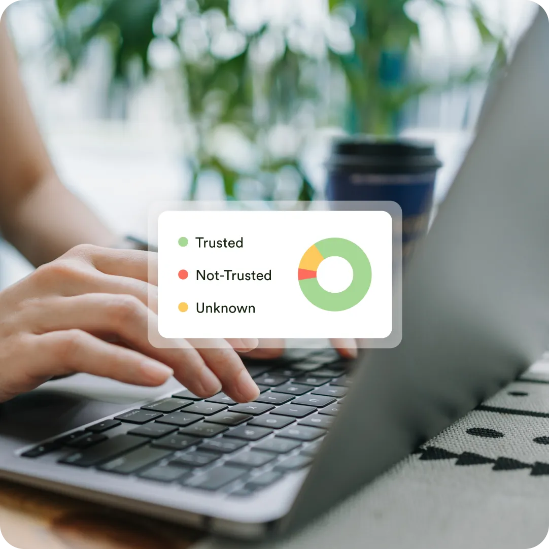 Hands typing on laptop with a foreground view of trusted, untrusted and unknown devices connected to a network.