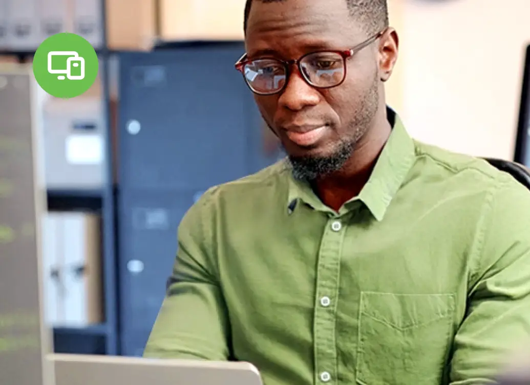 Man in glasses types on a laptop in an office