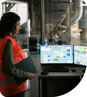 Woman holding a file in hand, focused on her computer screen