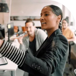 A woman sitting at a desk interacting with coworkers.