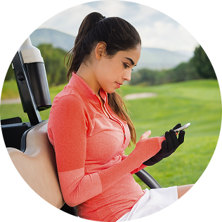 Person on golf cart with phone, golf course in background.